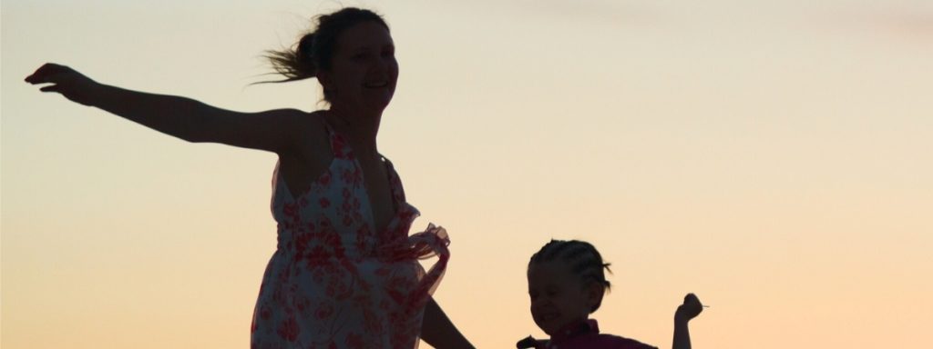 child and mom dancing outside silouhette