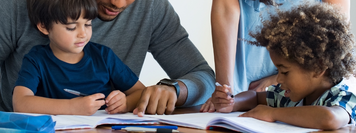 children writing in workbooks with their parents